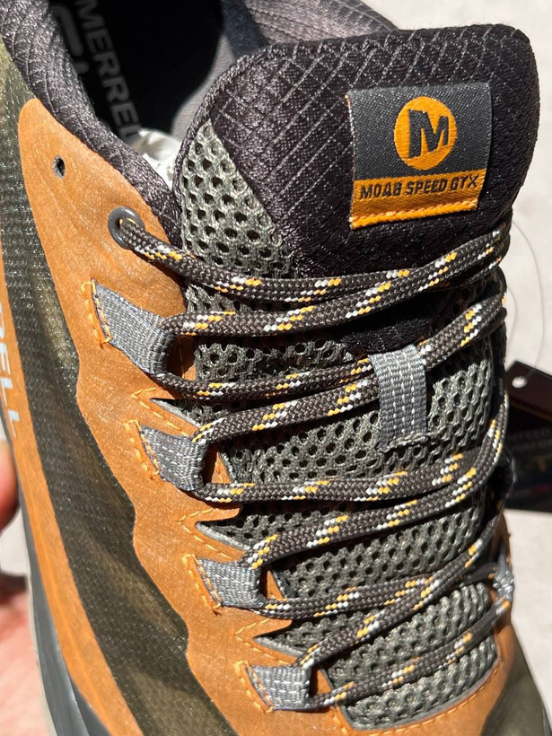 تصویر جزئیات (لوگو): نمای نزدیک از لوگوی Merrell و GORE-TEX روی بدنه کفش کوهنوردی Moab Speed
