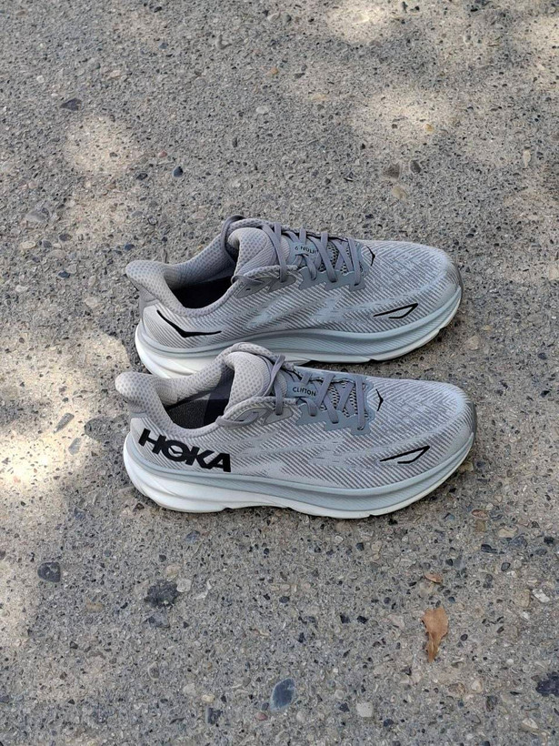 نمای جانبی کتونی هوکا مدل Hoka Clifton 9 طوسی با زیره ضخیم ضد شوک و لوگوی مشکی هوکا