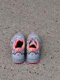 کفش رانینگ اسیکس ASICS GEL طوسی با جزئیات مرجانی، جفت کفش روی آسفالت